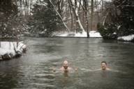 Two men swimming in the Eisbach in Munich in winter.
